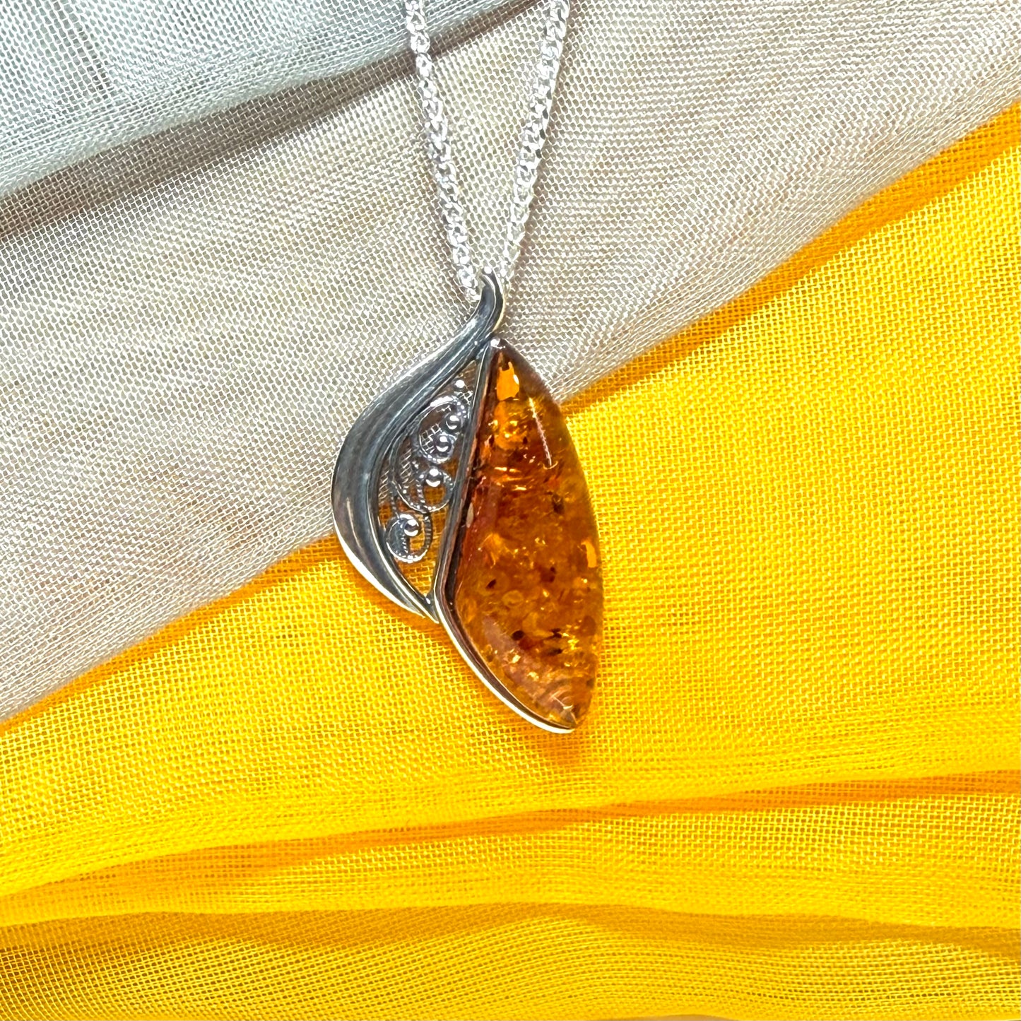 A Sterling silver real amber irregular marquise shaped necklace swirled open pendant