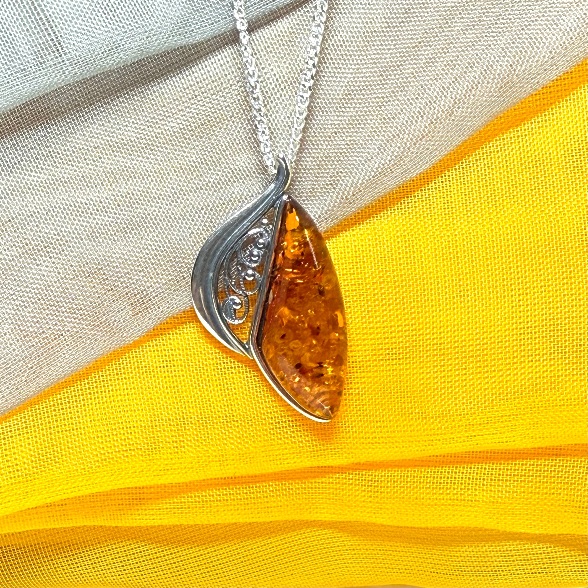A Sterling silver real amber irregular marquise shaped necklace swirled open pendant