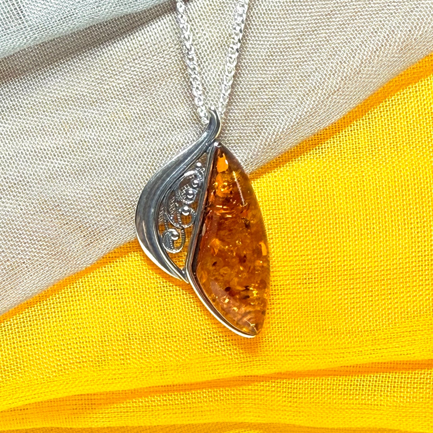 A Sterling silver real amber irregular marquise shaped necklace swirled open pendant