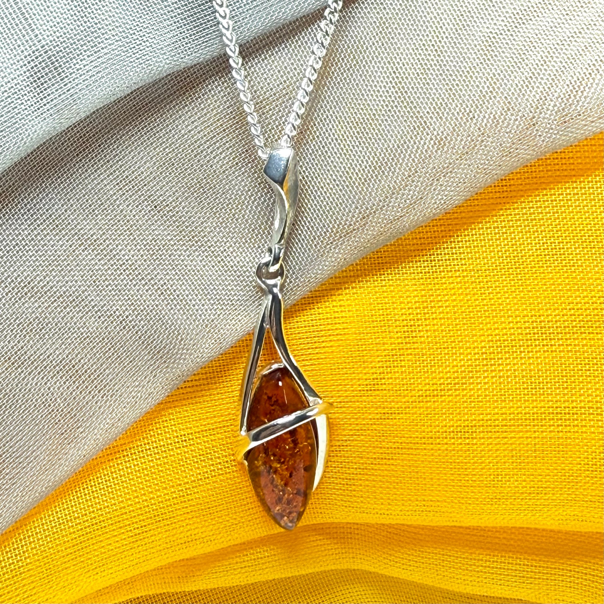 A Sterling silver real amber marquise shaped necklace swirled open pendant with chain