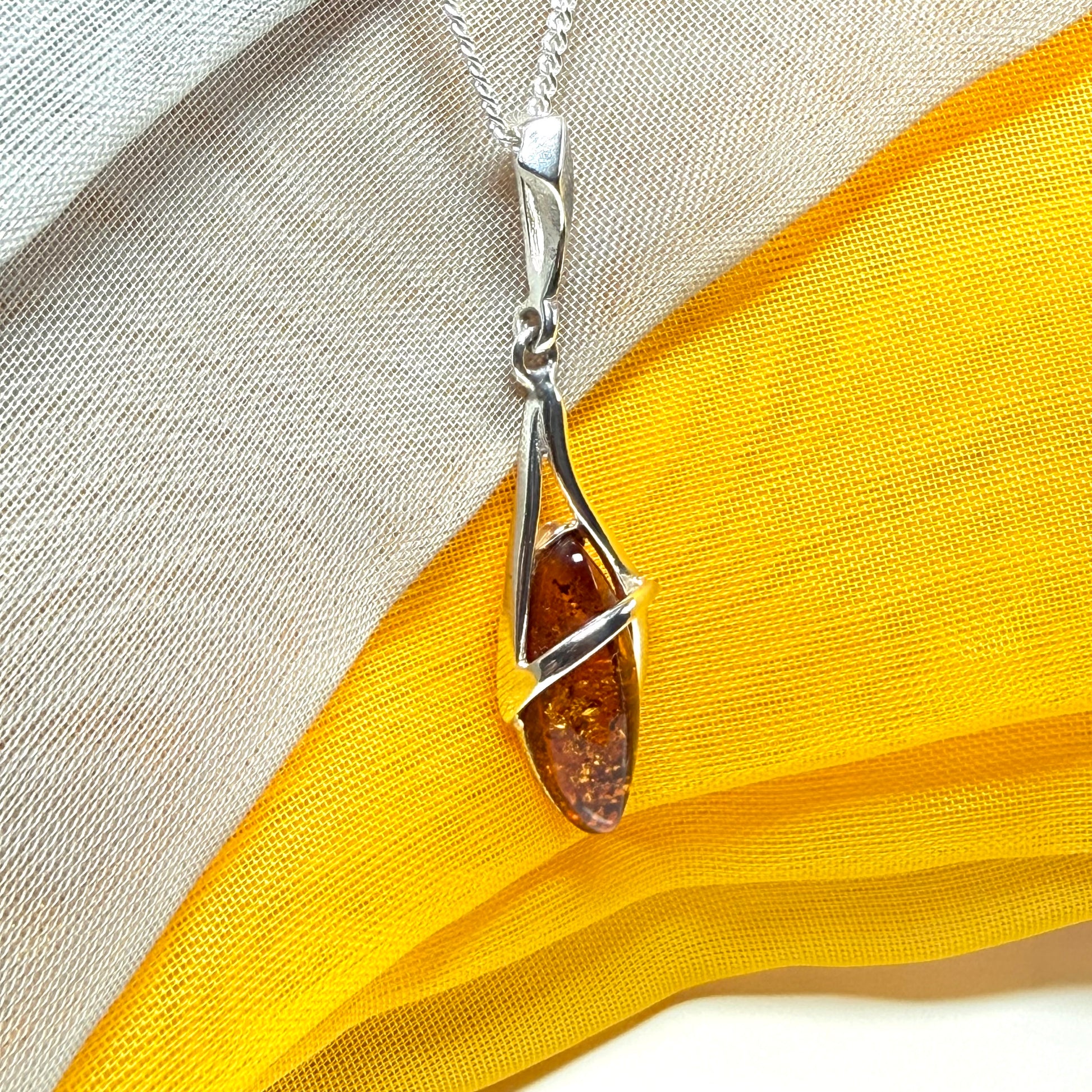 A Sterling silver real amber marquise shaped necklace swirled open pendant with chain