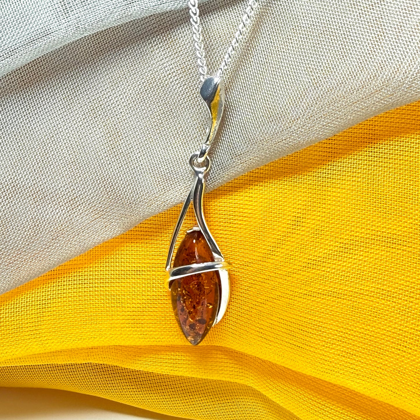 A Sterling silver real amber marquise shaped necklace swirled open pendant with chain