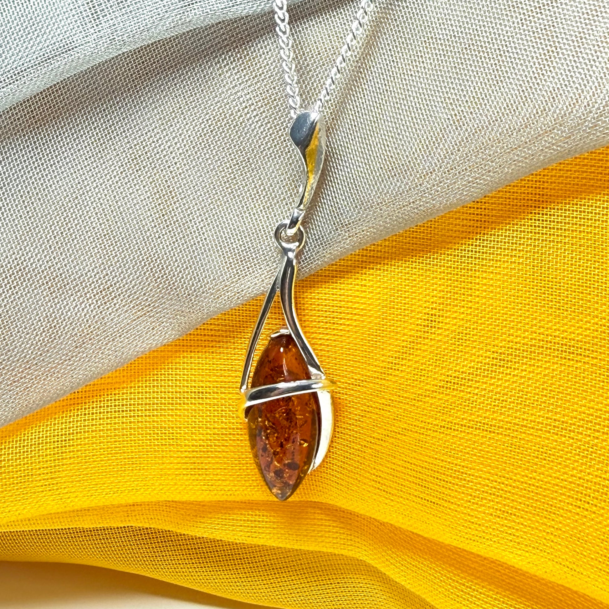 A Sterling silver real amber marquise shaped necklace swirled open pendant with chain