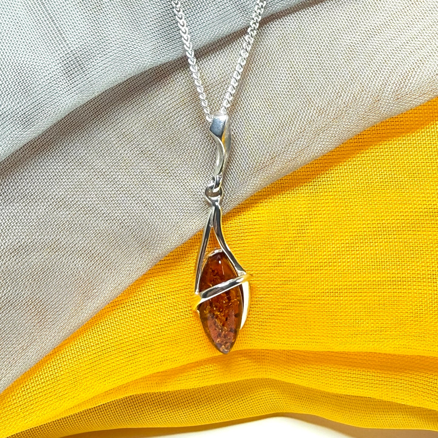A Sterling silver real amber marquise shaped necklace swirled open pendant with chain