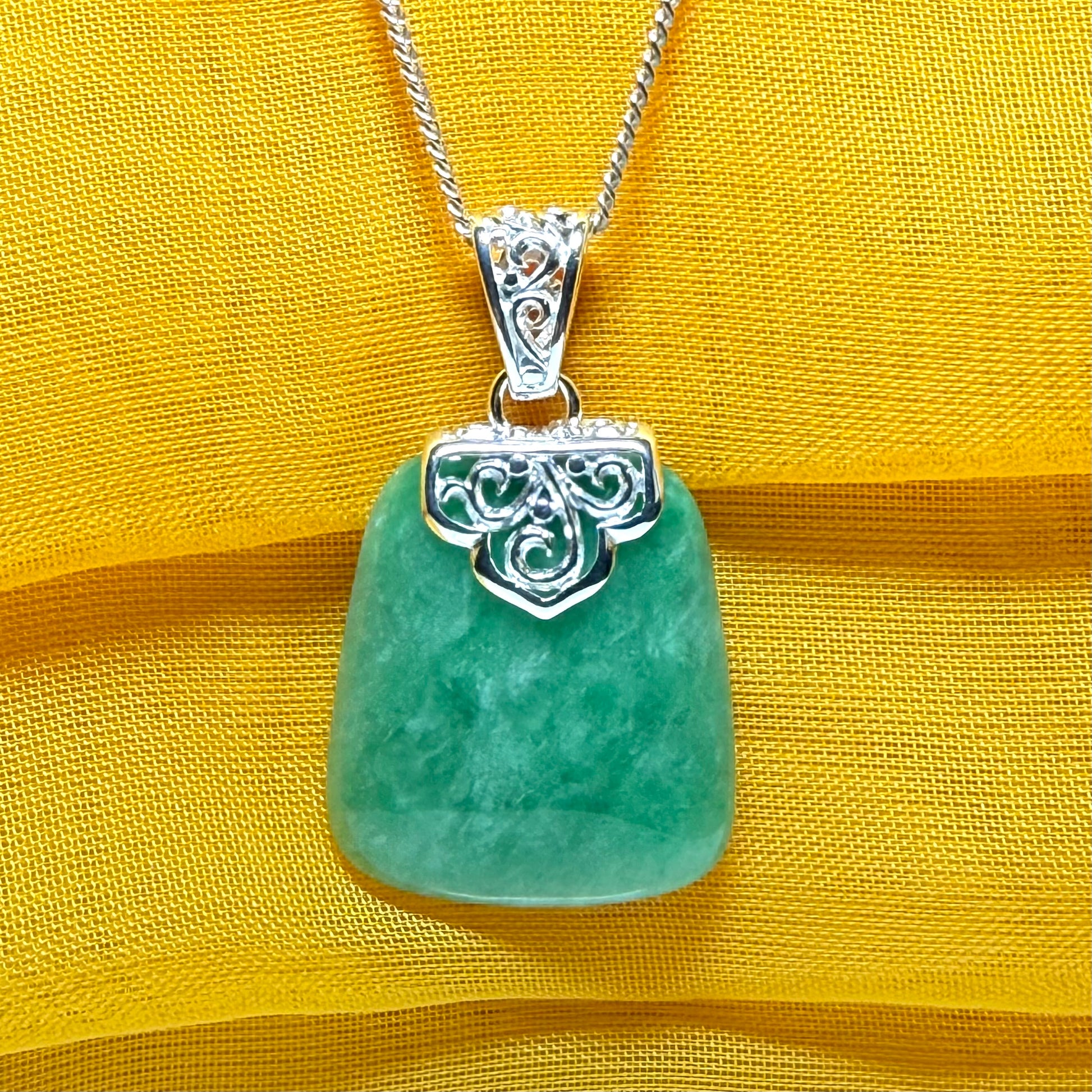 A real green jade necklace with a large shaped and patterned top pendant