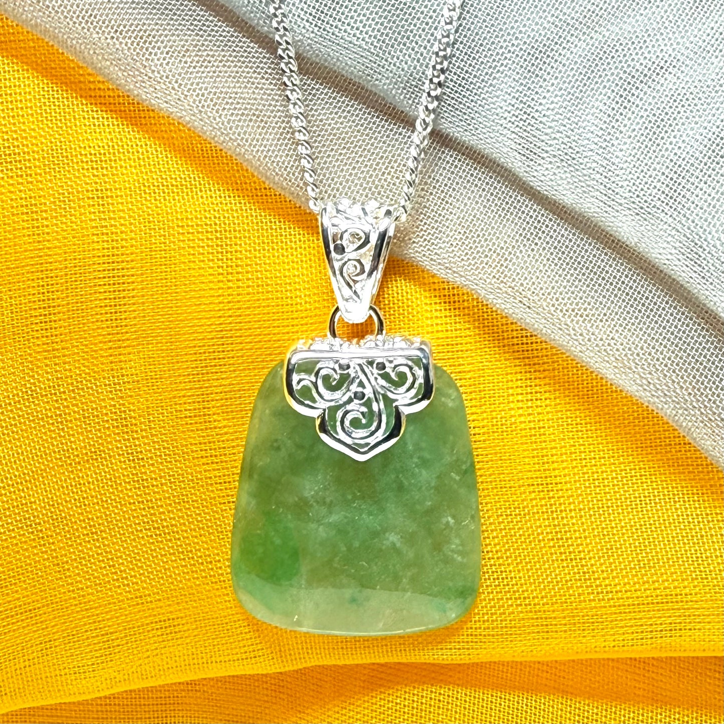 A green real jade necklace with a large shaped and patterned pendant with a chain