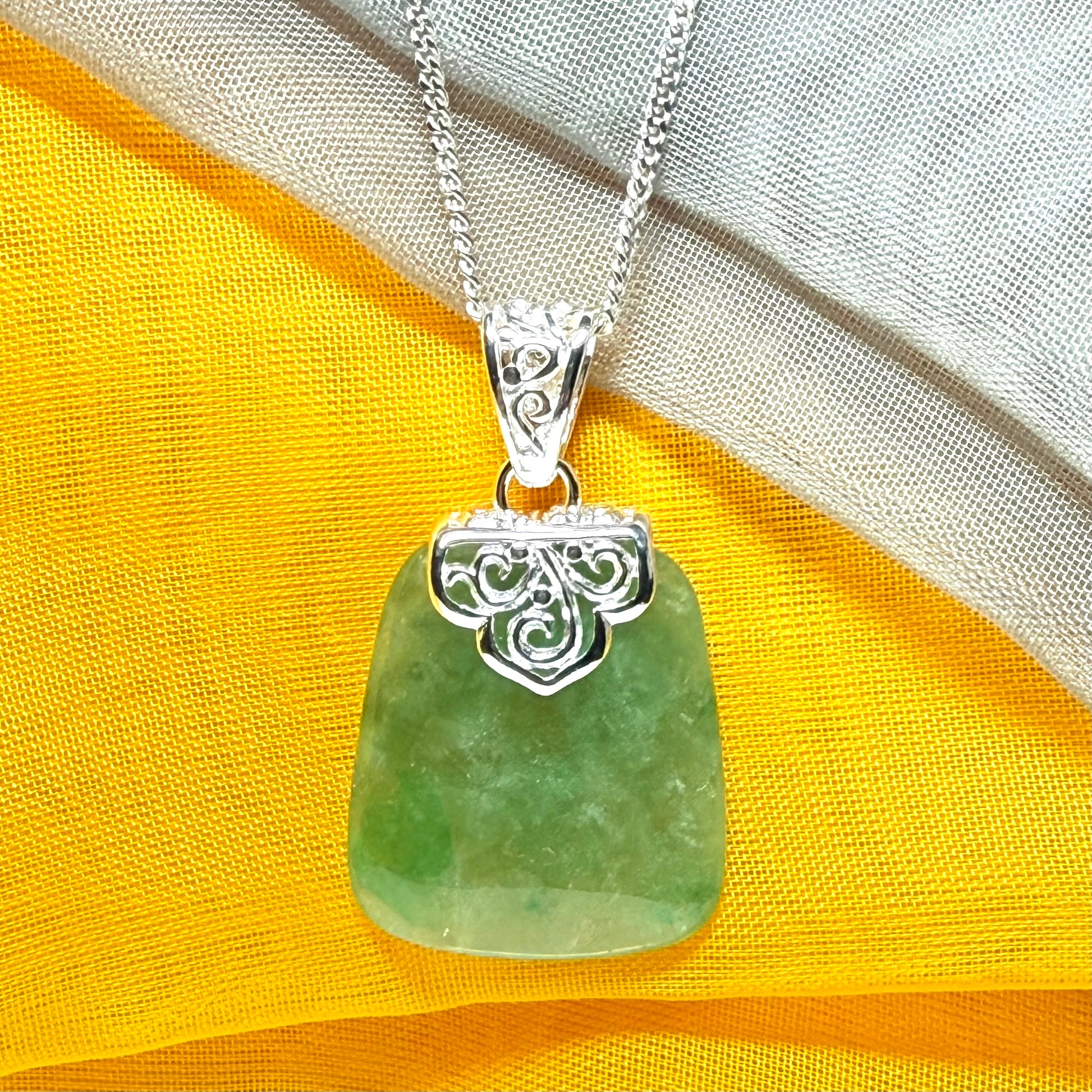 A green real jade necklace with a large shaped and patterned pendant with a chain
