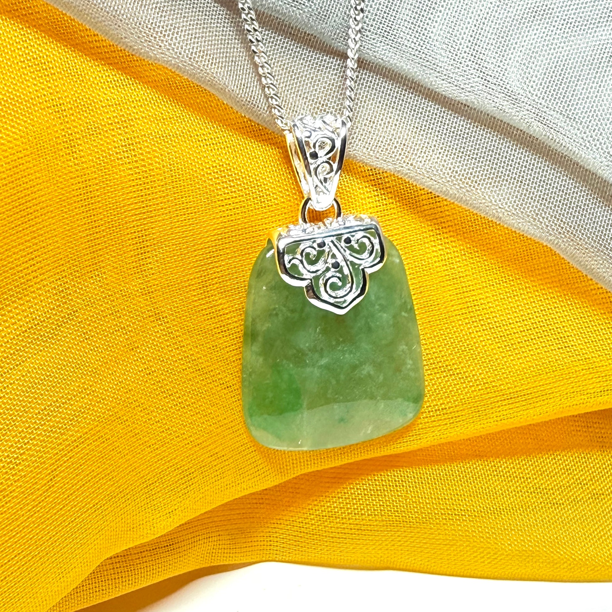 A green real jade necklace with a large shaped and patterned pendant with a chain