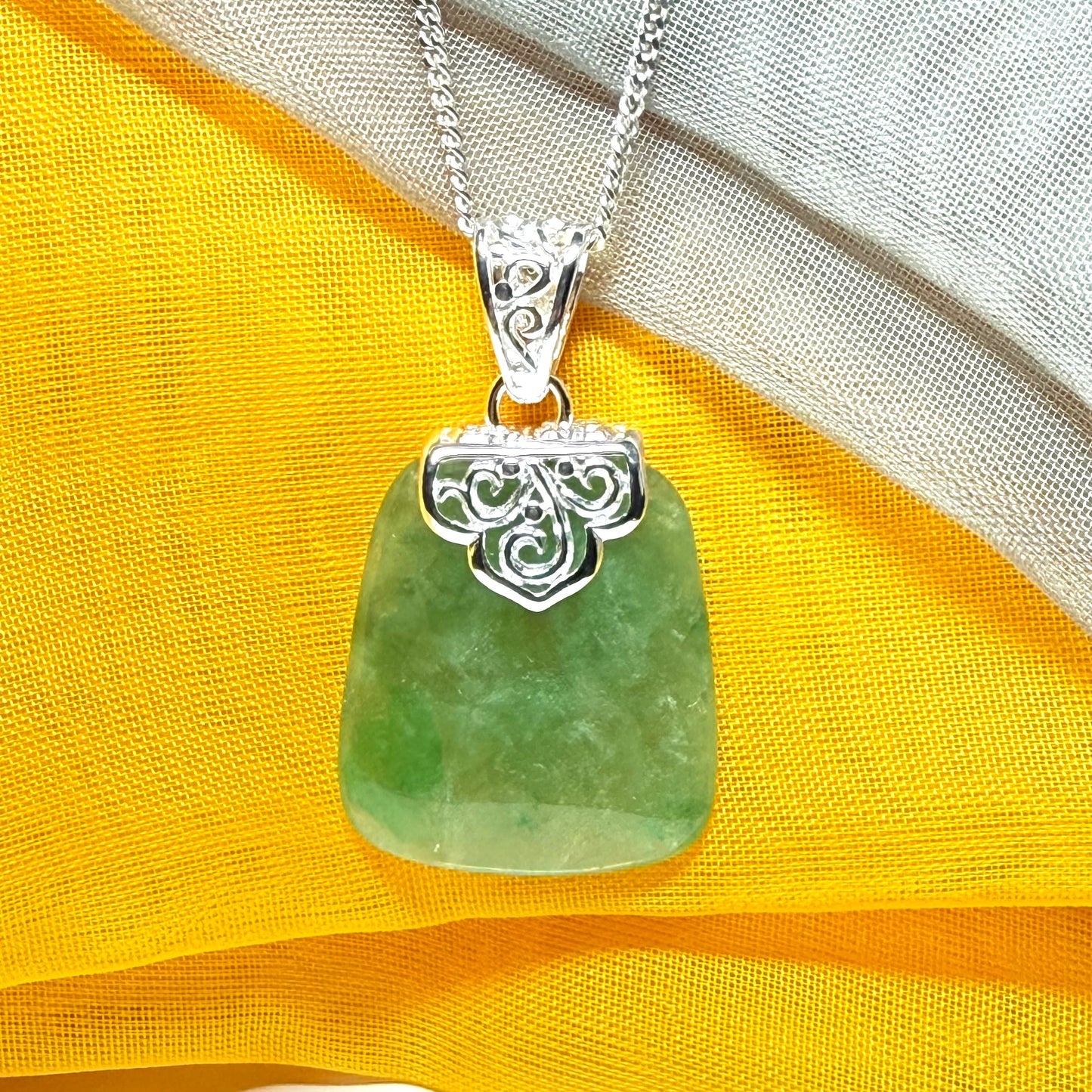 A green real jade necklace with a large shaped and patterned pendant with a chain