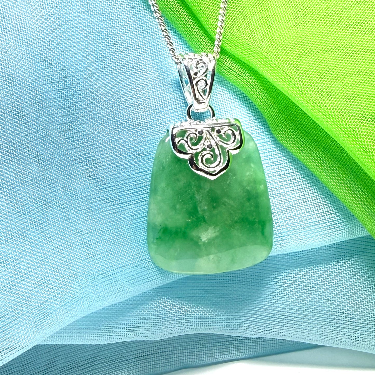 A green real jade necklace with a large shaped and patterned pendant with chain