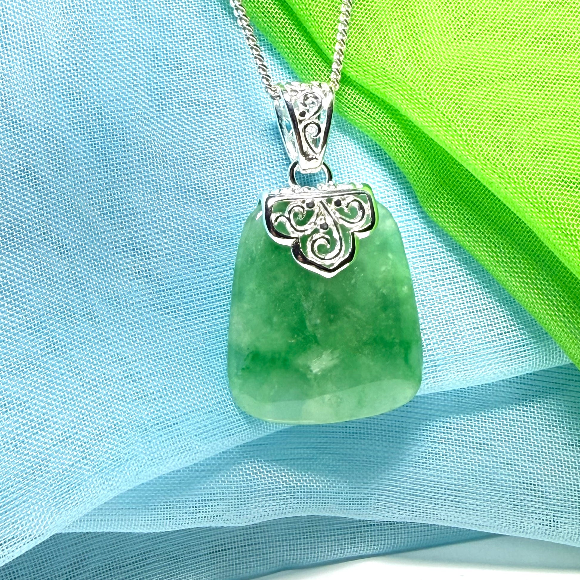 A green real jade necklace with a large shaped and patterned pendant with chain