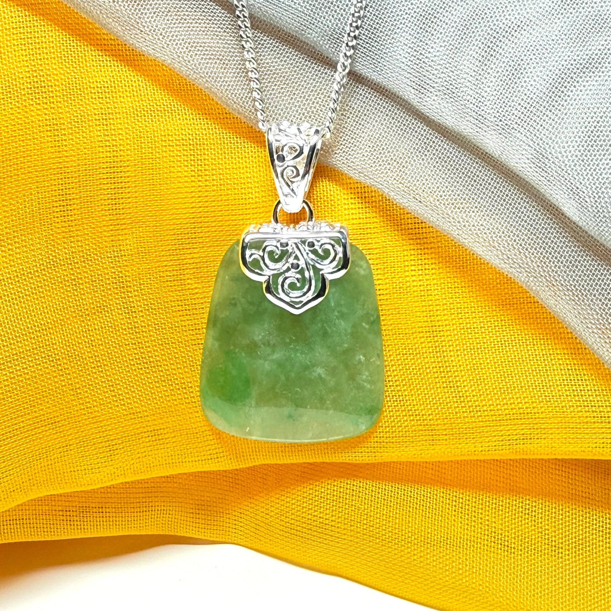 A green real jade necklace with a large shaped and patterned pendant with a chain