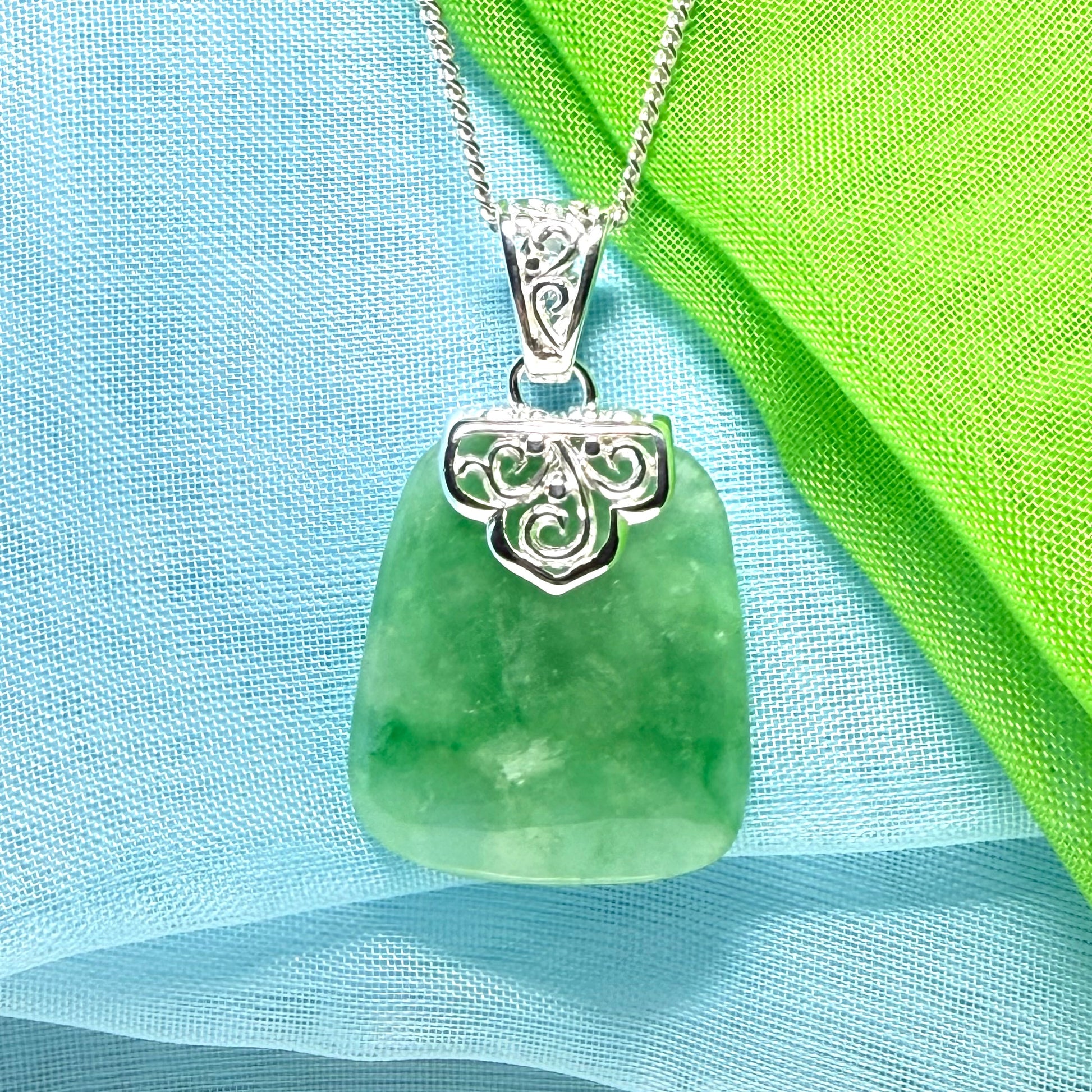 A green real jade necklace with a large shaped and patterned pendant with chain