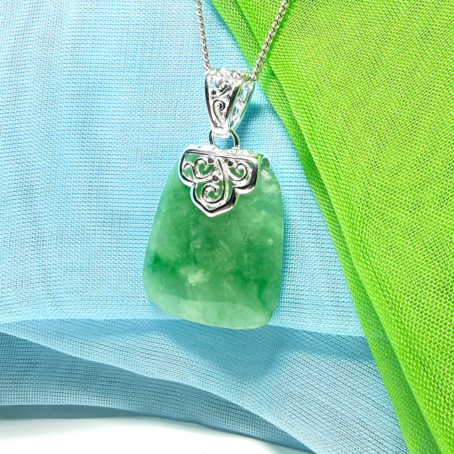 A green real jade necklace with a large shaped and patterned pendant with chain