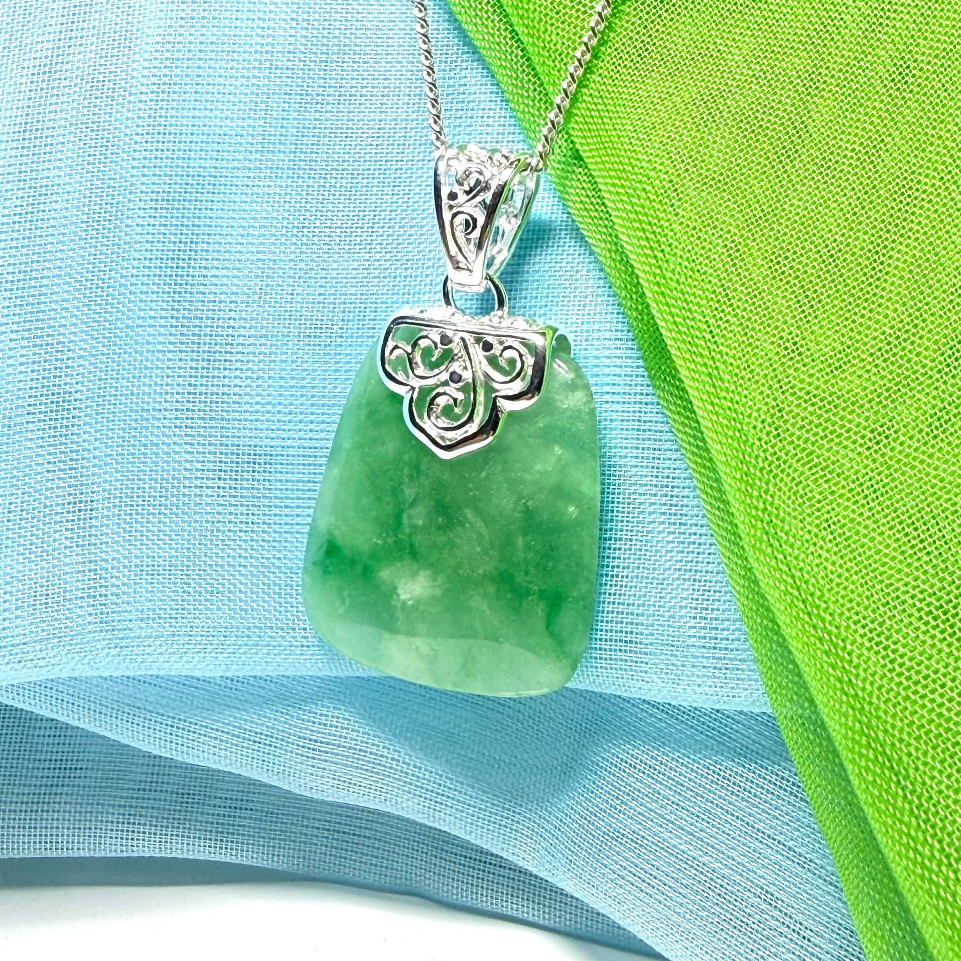 A green real jade necklace with a large shaped and patterned pendant with chain