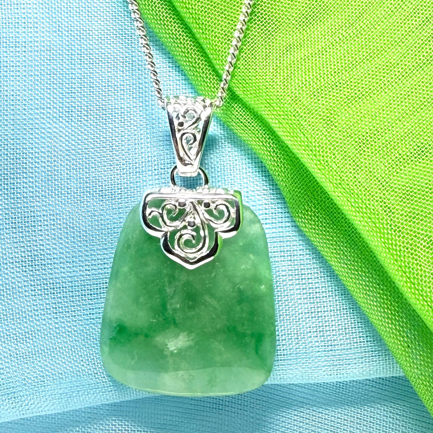 A green real jade necklace with a large shaped and patterned pendant with chain