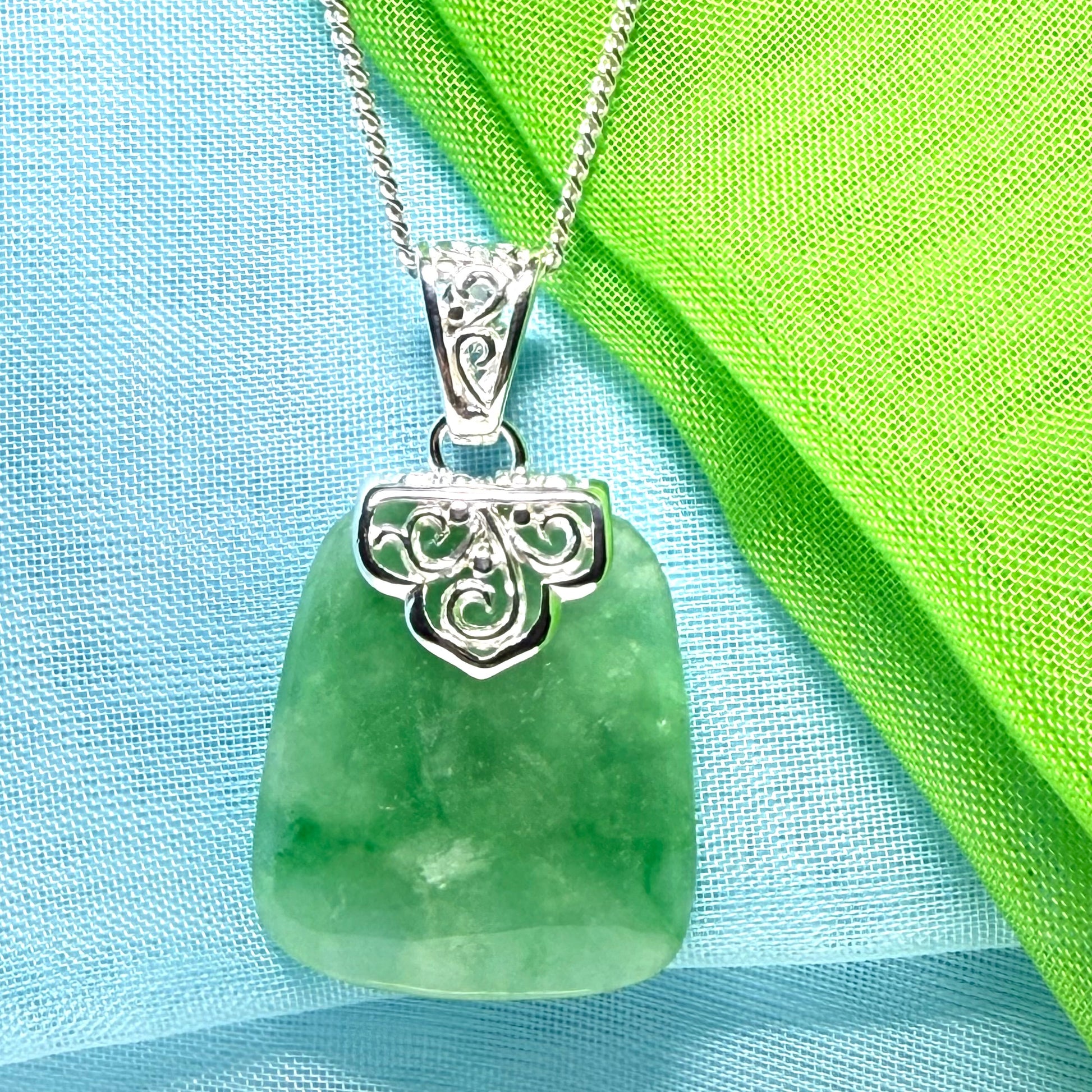 A green real jade necklace with a large shaped and patterned pendant with chain