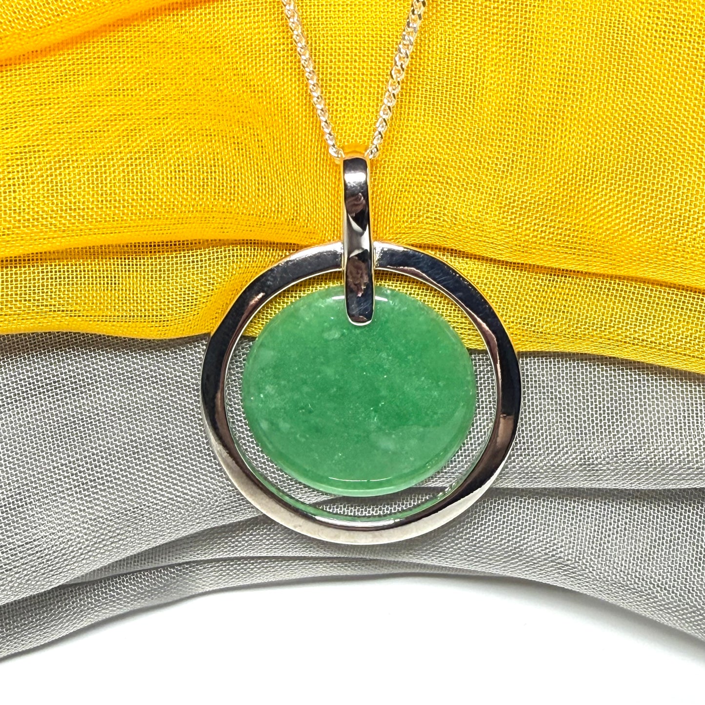 Green pendant necklace on a yellow fabric background