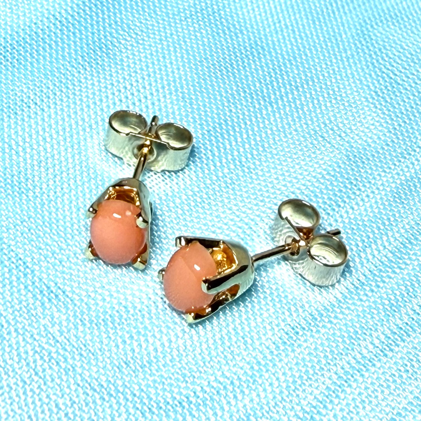 A pair of oval shaped real coral stud earrings yellow gold four claw set
