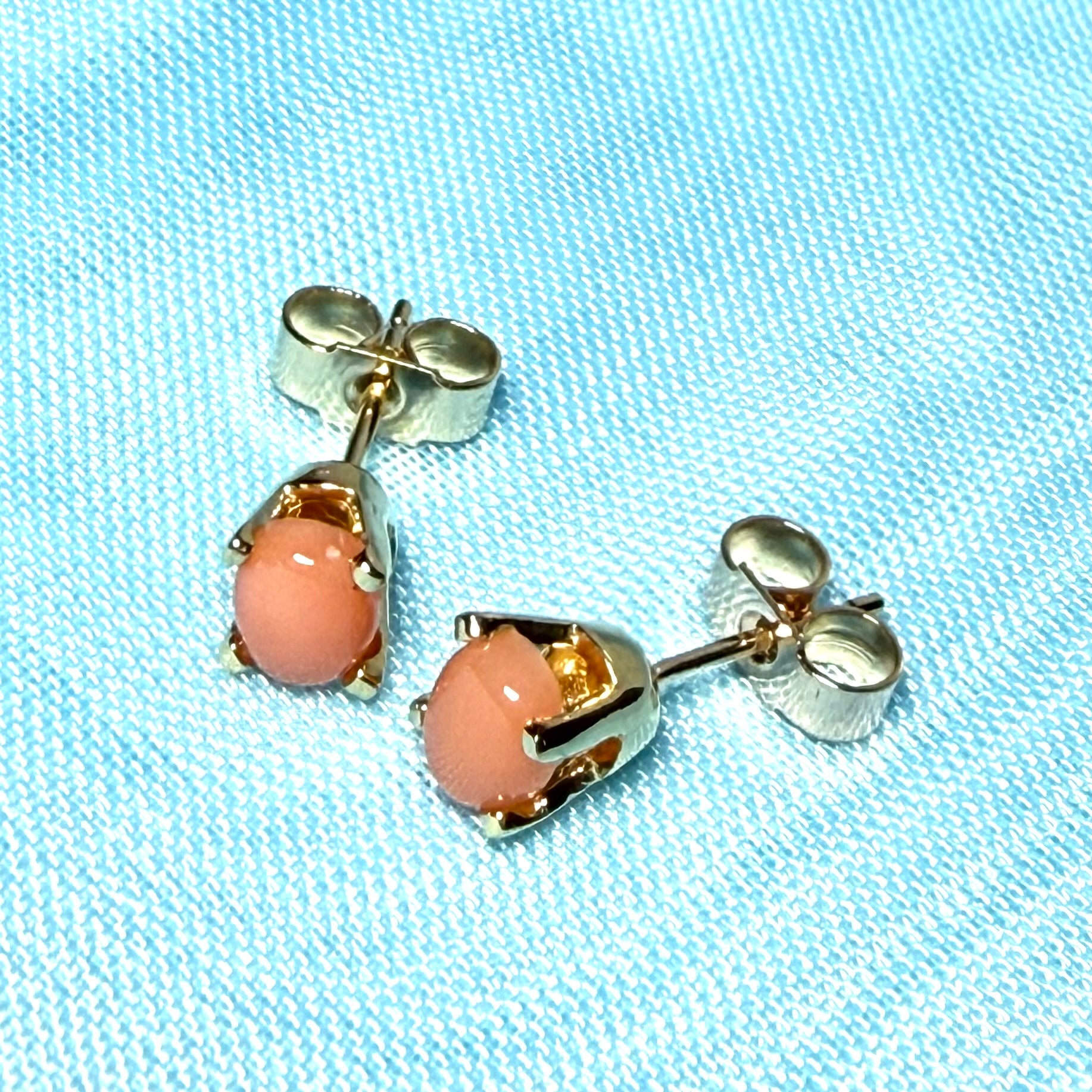 A pair of oval shaped real coral stud earrings yellow gold four claw set