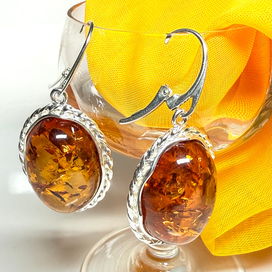 A pair of real amber drop earrings an oval shape rope edge sterling silver continental wire fittings