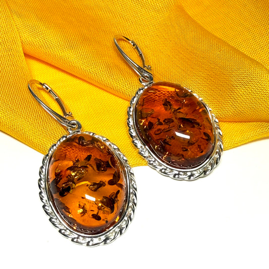 A pair of real amber drop earrings an oval shape rope edge sterling silver continental wire fittings