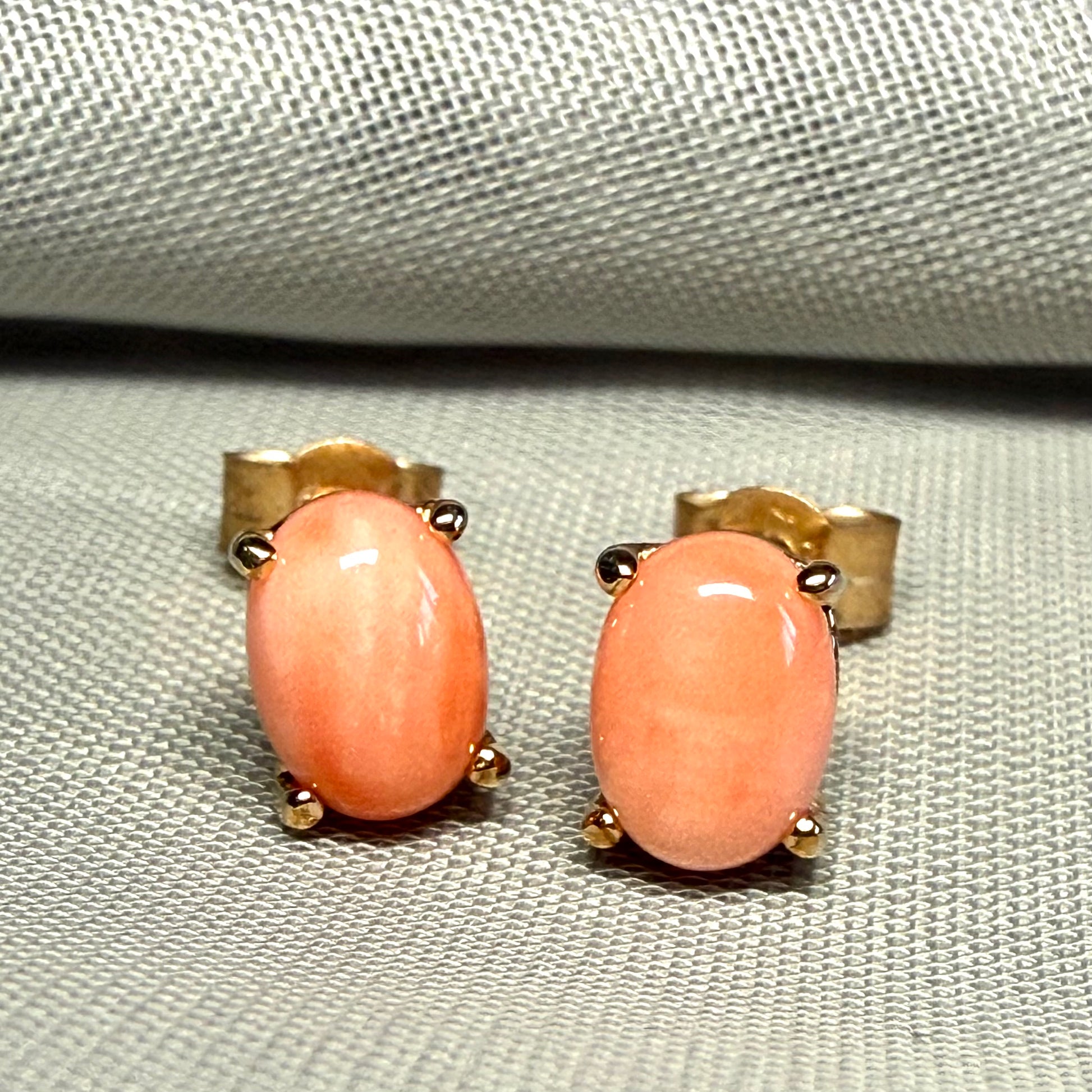 A pair of real coral oval shaped stud earrings yellow gold claw set
