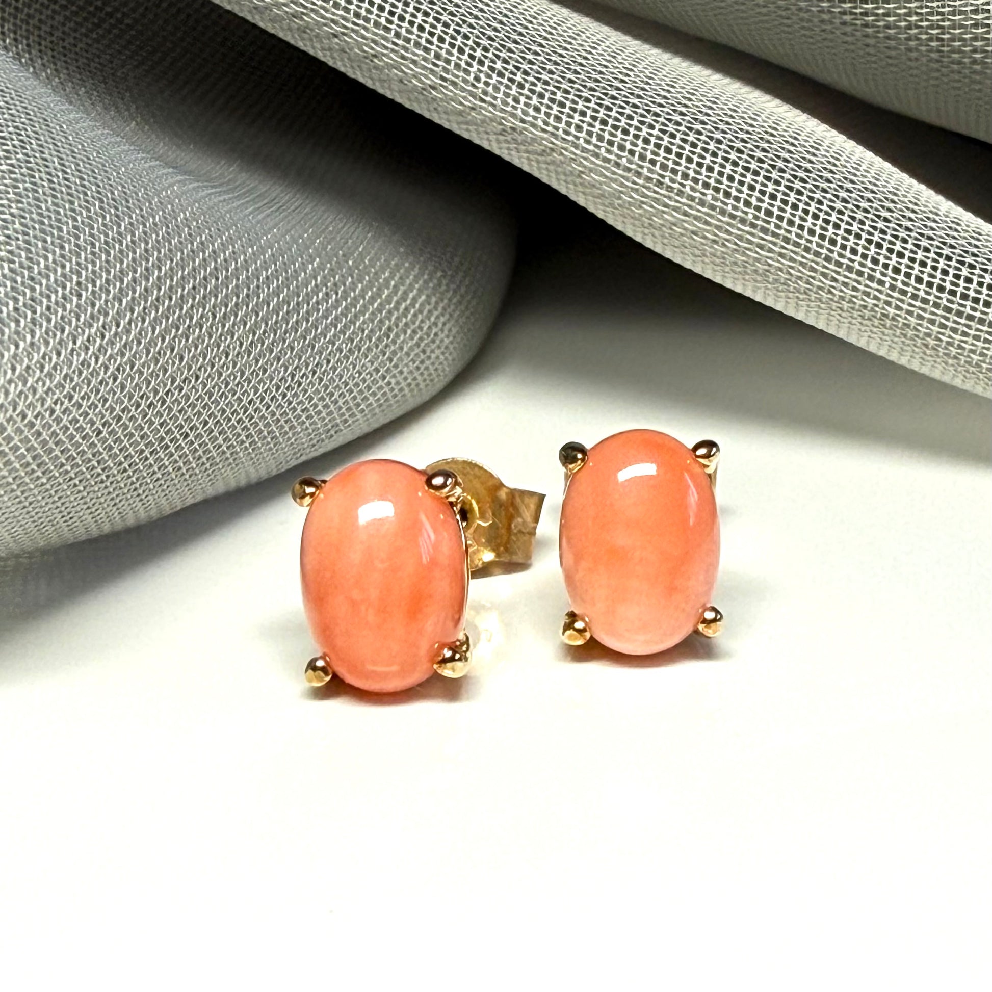 A pair of real coral oval shaped stud earrings yellow gold claw set