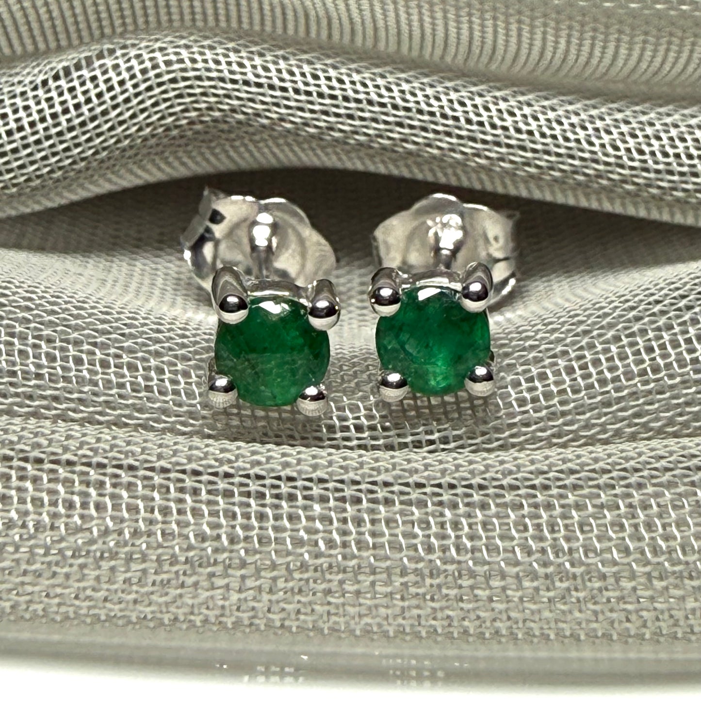 A pair of real green emerald earrings round white gold claw set studs