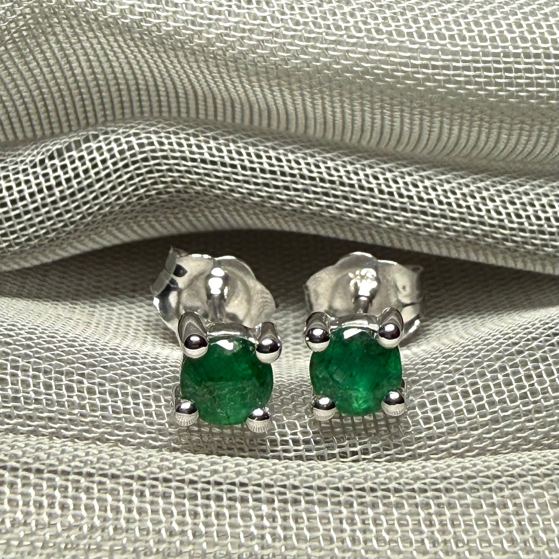 A pair of real green emerald earrings round white gold claw set studs