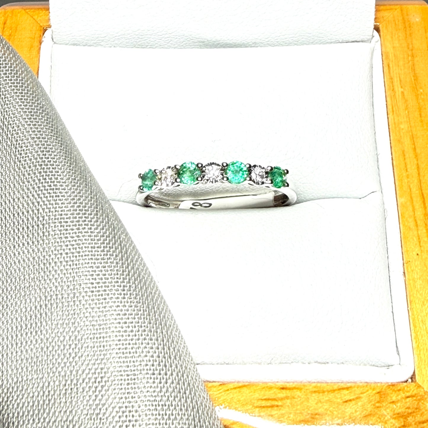 A real emerald and diamond white gold eternity ring claw setting