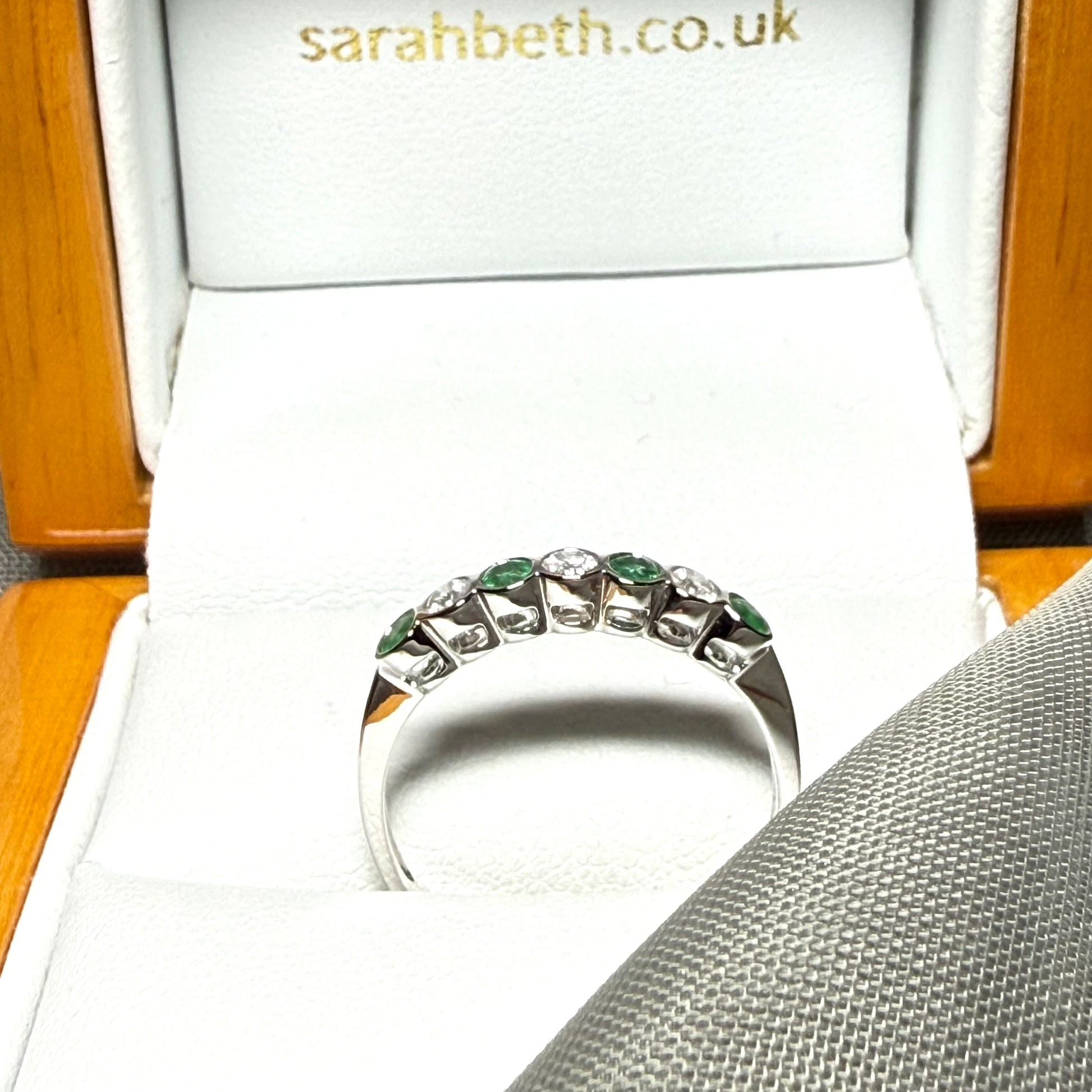A real emerald and diamond white gold eternity ring with smooth setting