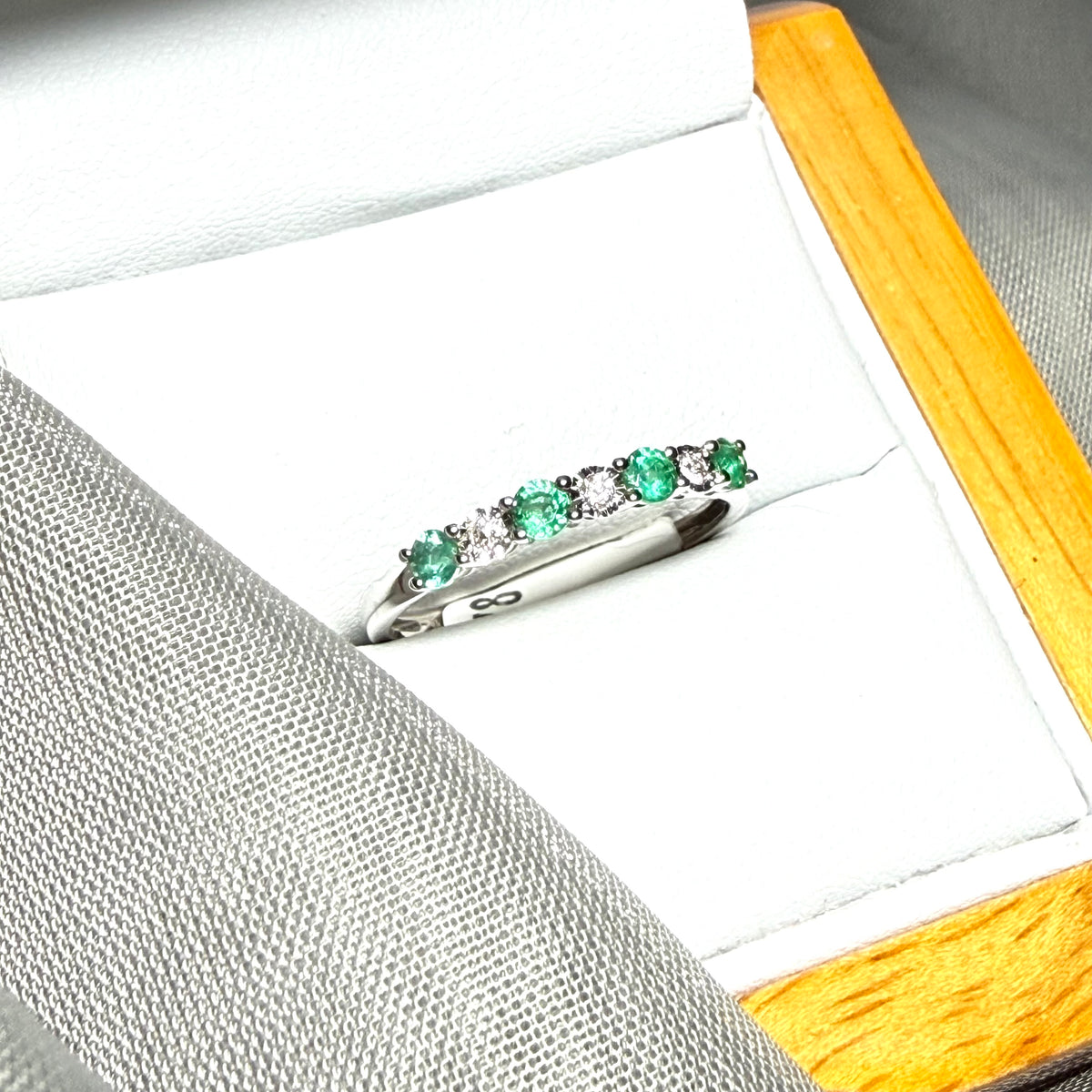 A real emerald and diamond white gold eternity ring claw setting