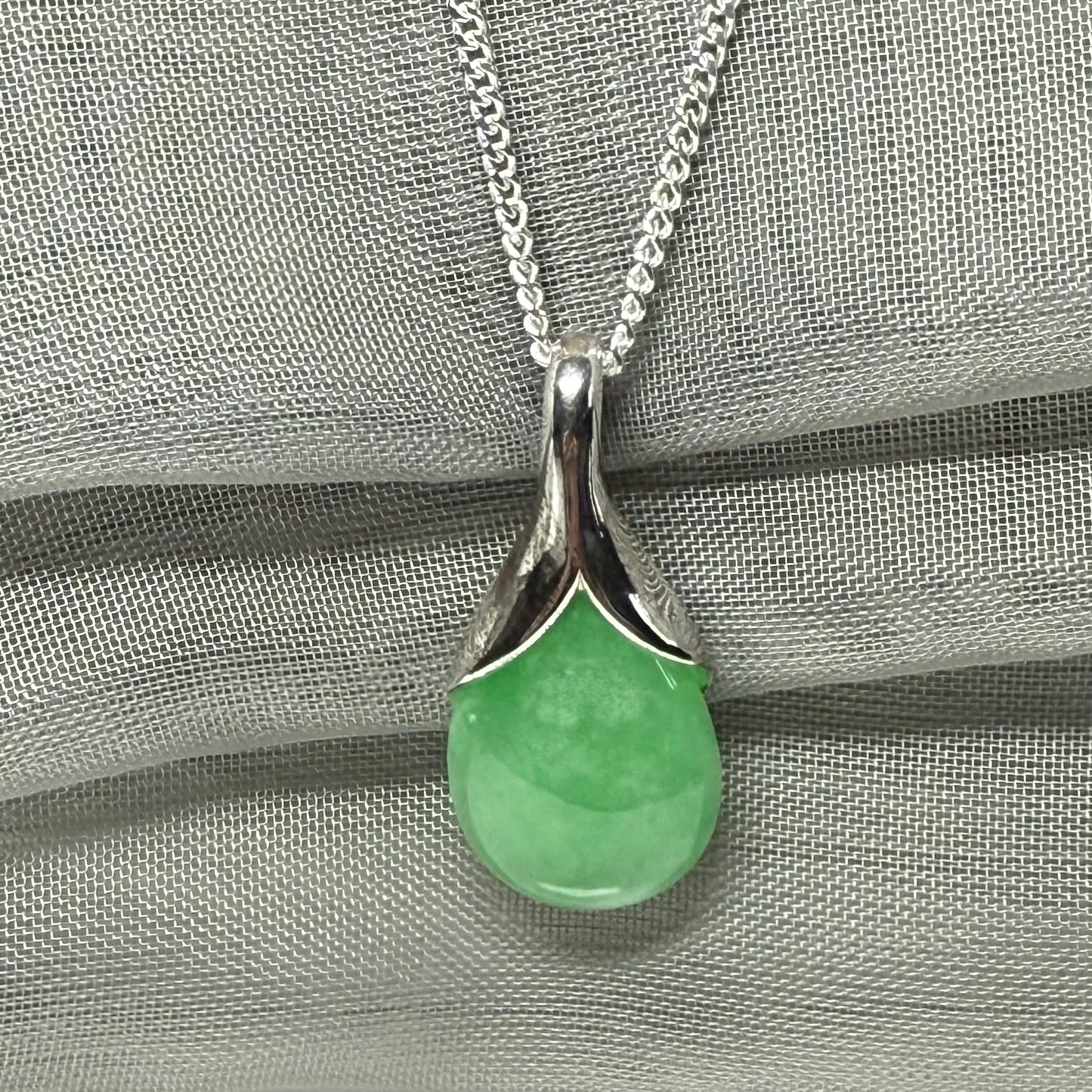 A real green jade necklace in a teardrop or a pear shape including a solid with a chain included