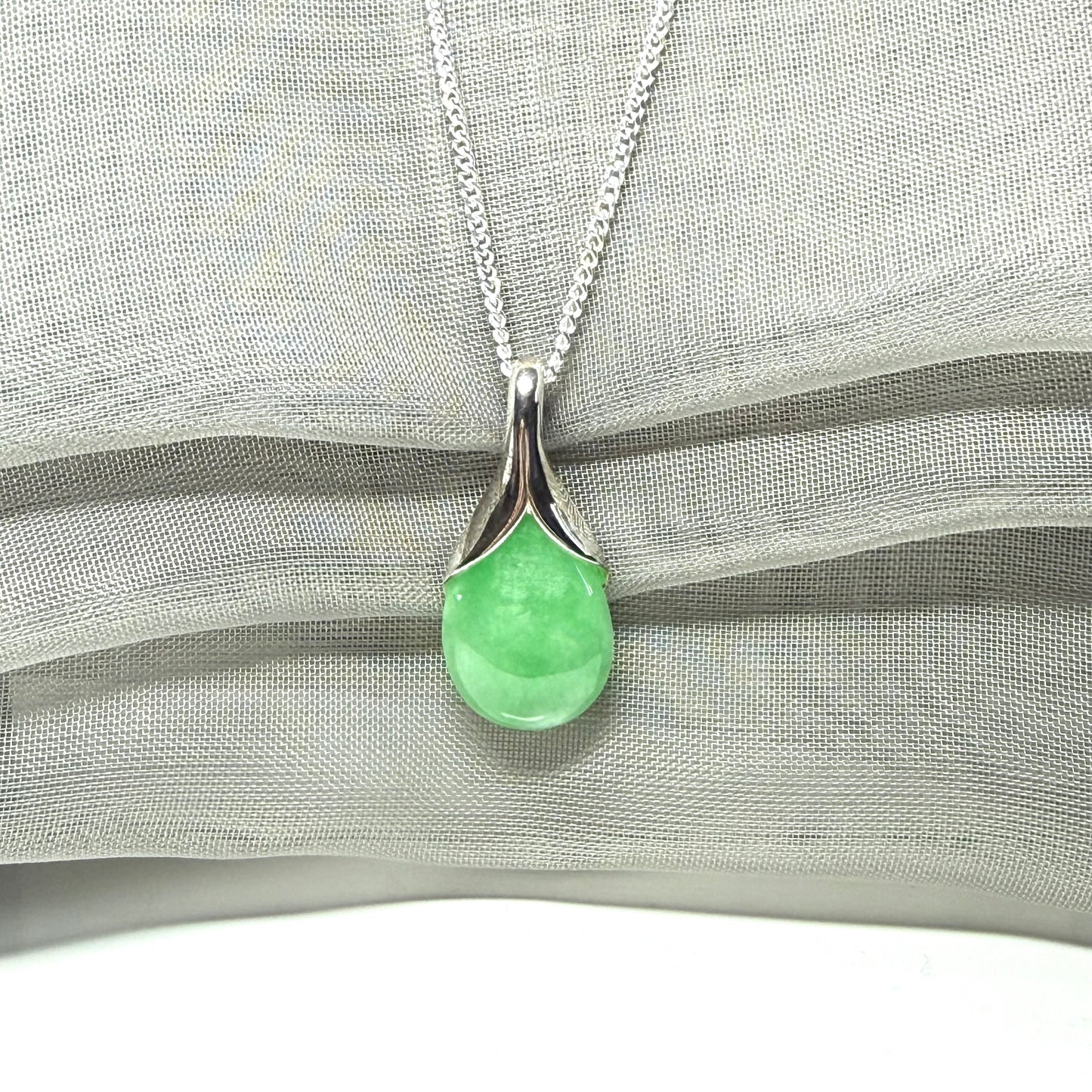 A real green jade necklace in a teardrop or a pear shape including a solid with a chain included