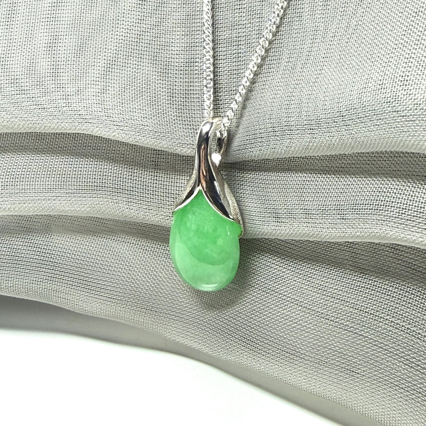A real green jade necklace in a teardrop or a pear shape including a solid with a chain included