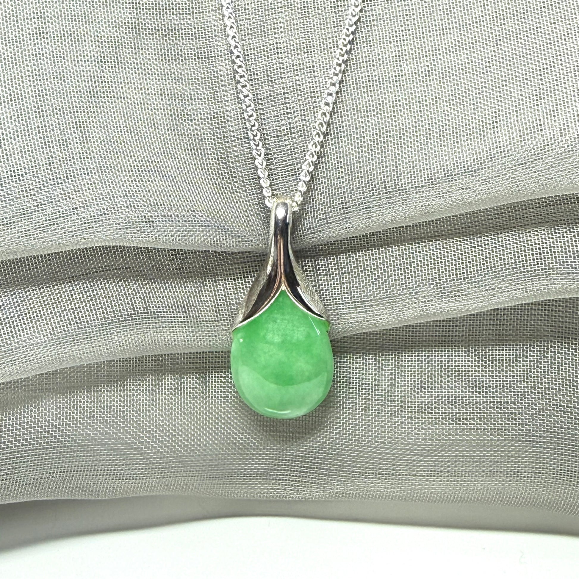A real green jade necklace in a teardrop or a pear shape including a solid with a chain included