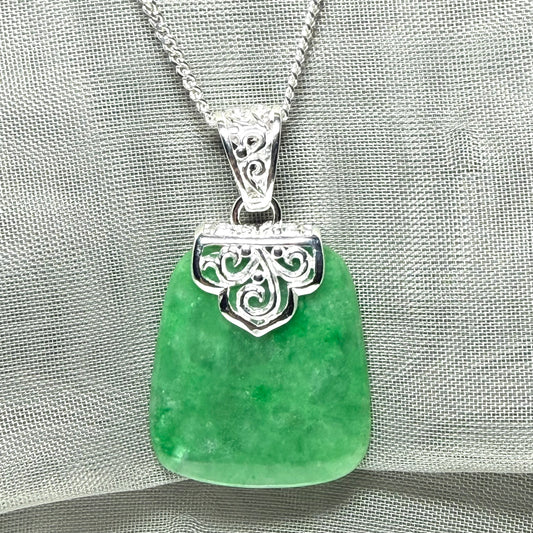 A real green jade necklace large shaped with a patterned top pendant to it