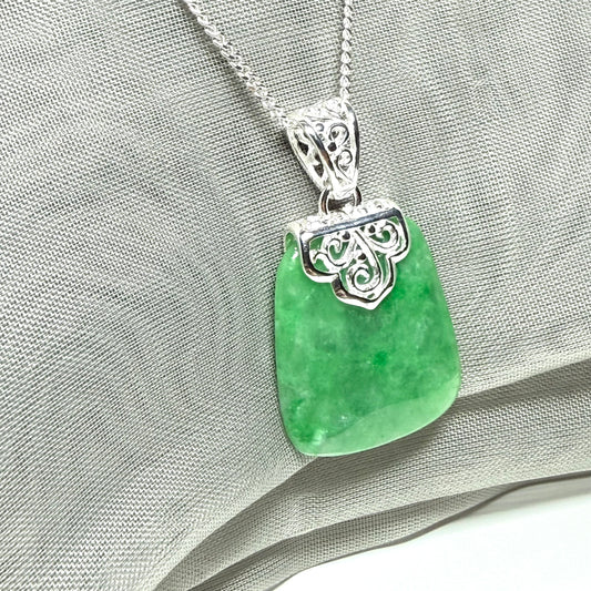 A real green jade necklace large shaped with a patterned top pendant to it