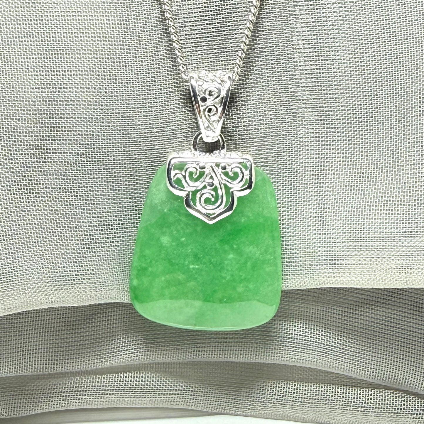 A real green jade necklace with a large shaped and patterned pendant