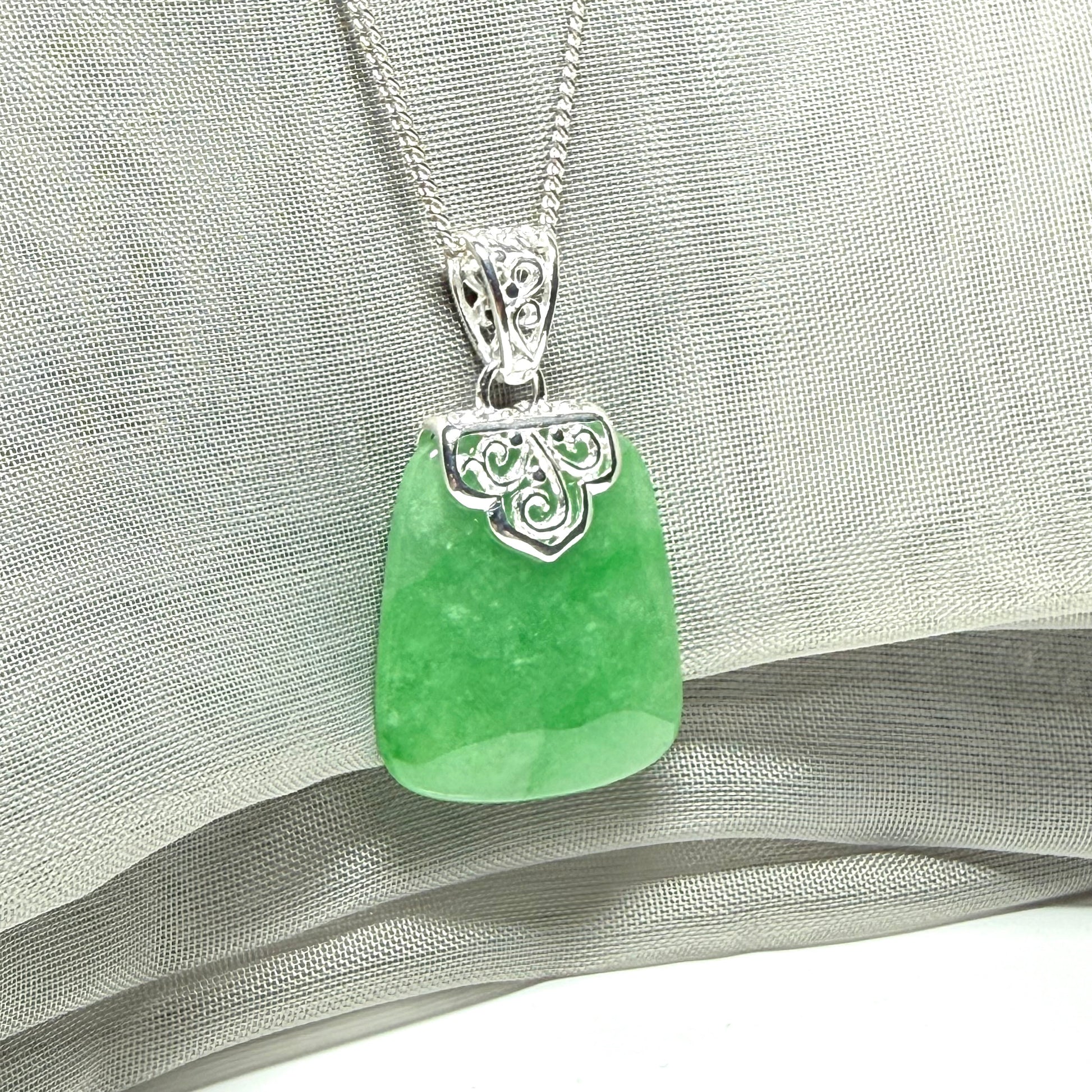 A real green jade necklace with a large shaped and patterned pendant