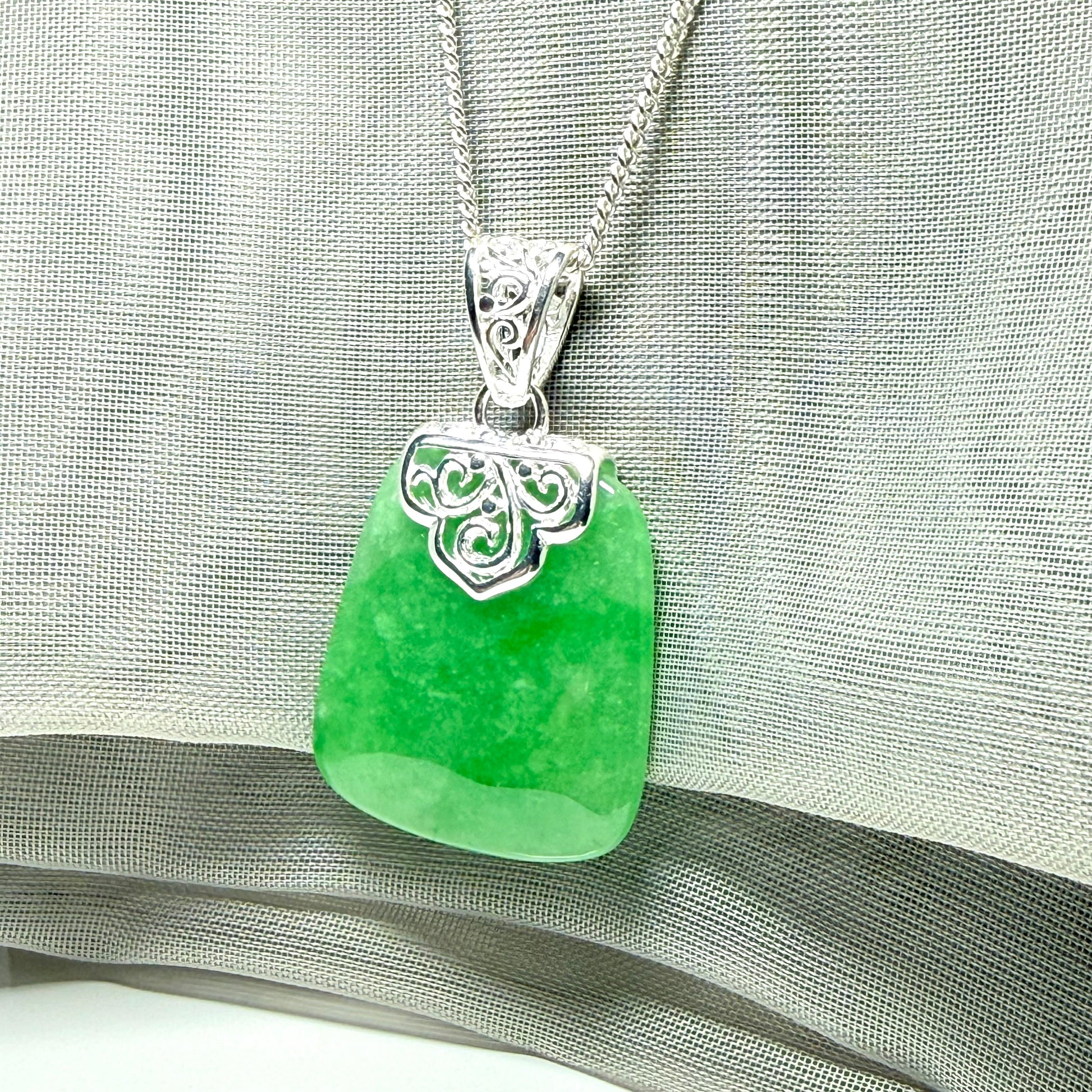 A real green jade necklace with a large shaped and patterned pendant