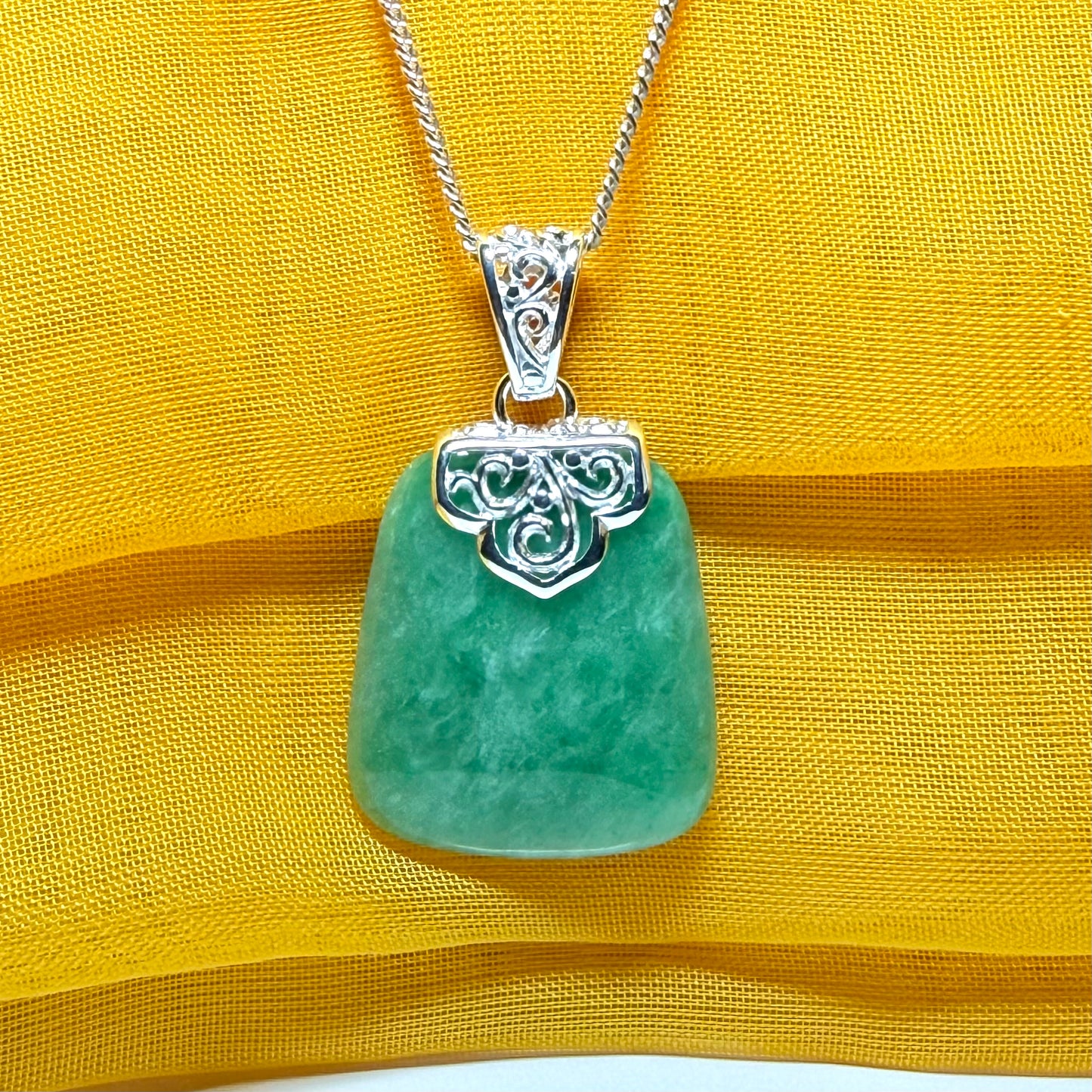 A real green jade necklace with a large shaped and patterned top pendant