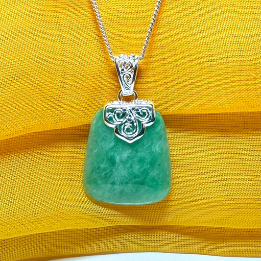 A real green jade necklace with a large shaped and patterned top pendant