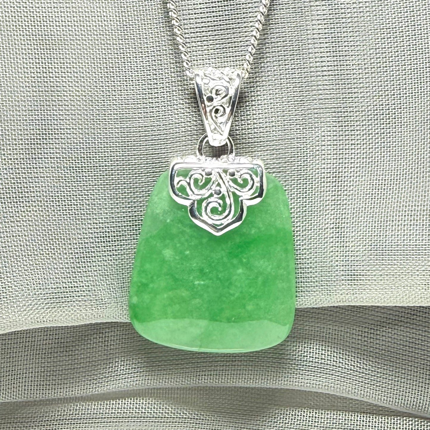 A real green jade necklace with a large shaped and patterned pendant