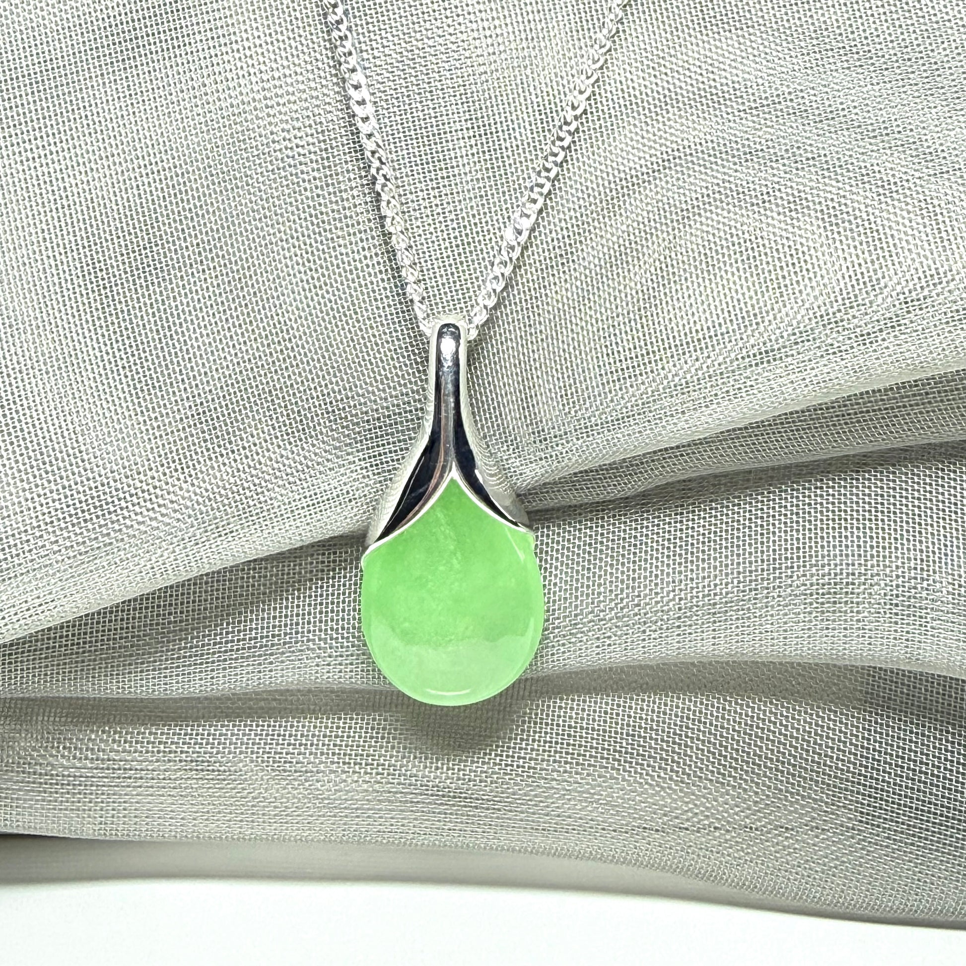 A real green jade pendant necklace in a teardrop shape or pear shaped design