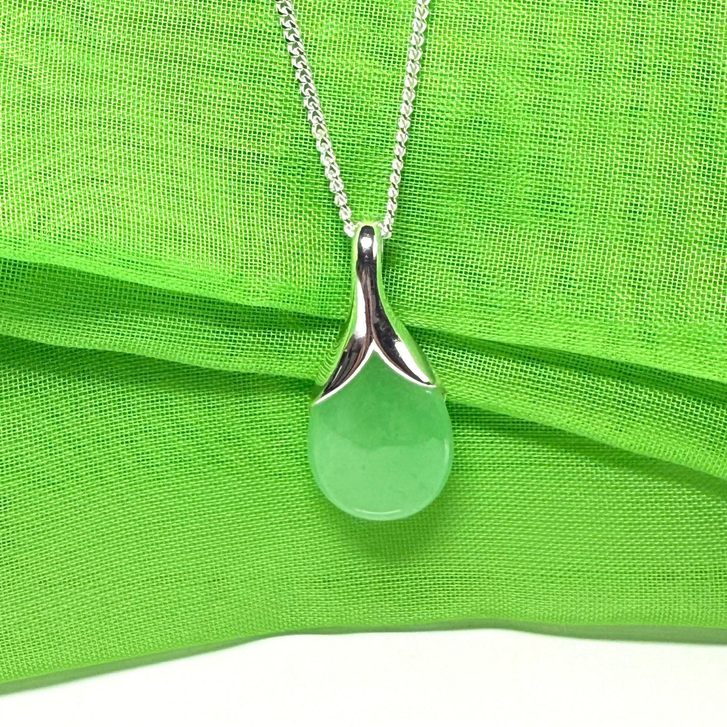 A real green jade pendant necklace in a teardrop shaped or pear shaped design to it