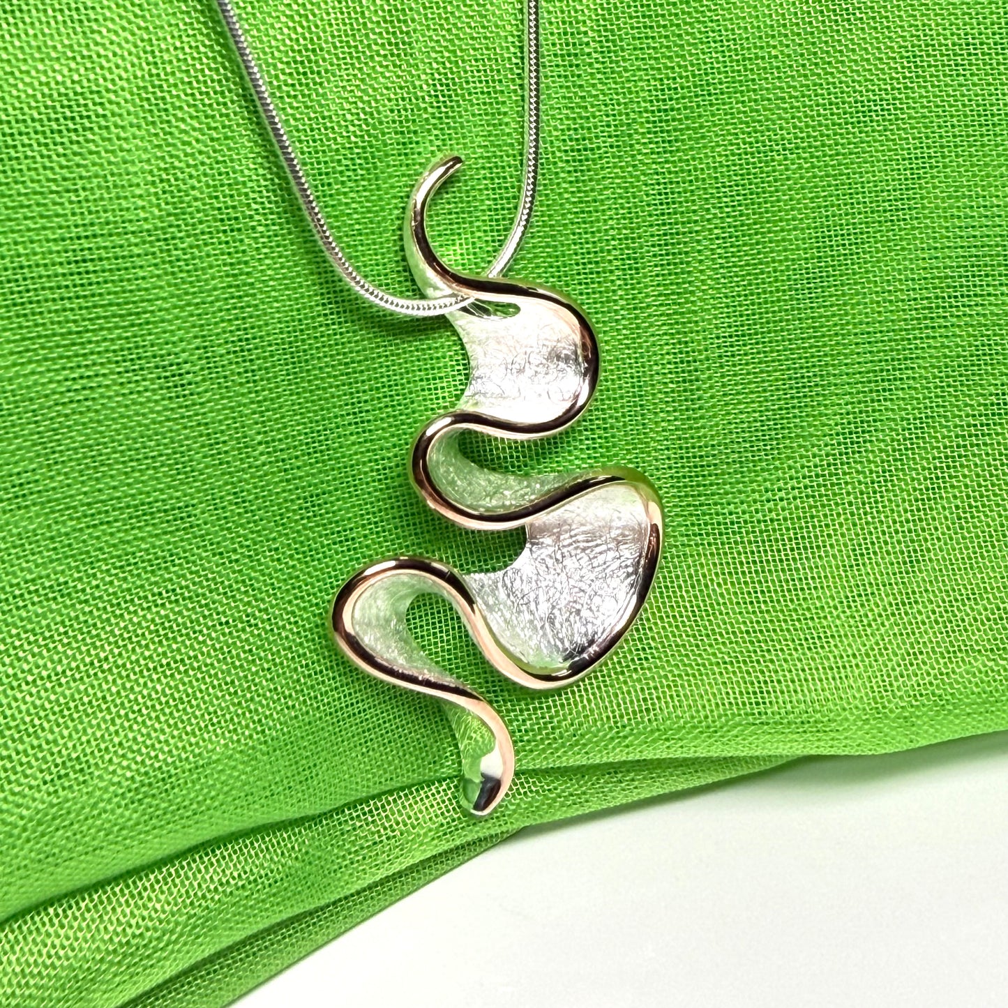 A sterling silver solid rounded open pierced fancy swirl necklace with snake chain