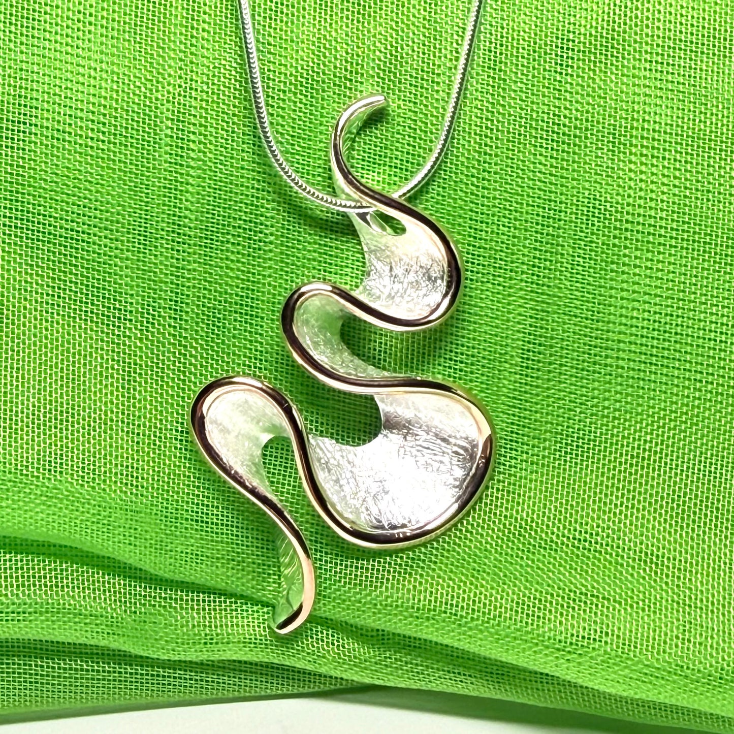 A sterling silver solid rounded open pierced fancy swirl necklace with snake chain