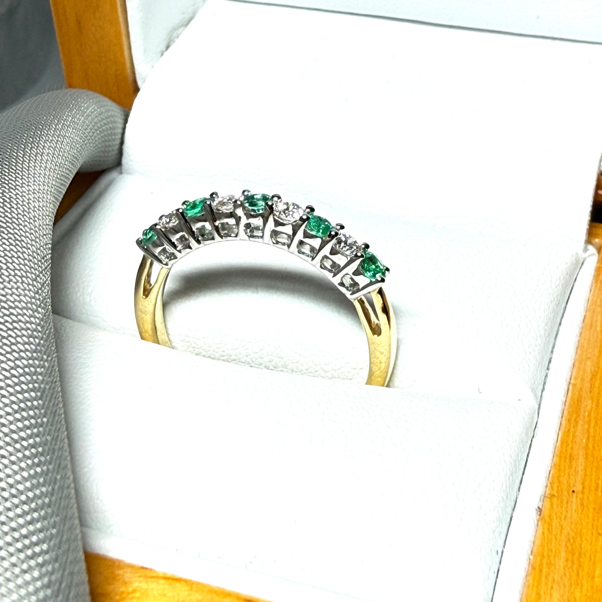 A stunning real emerald and diamond yellow gold eternity ring claw setting